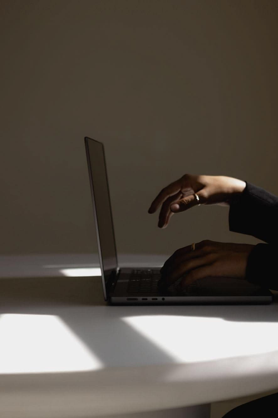 Manos escribiendo en un portátil bajo la luz de una ventana