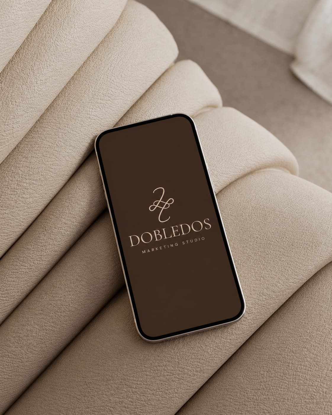 Móvil con el logotipo de Dobledos sobre un sofá tapizado en tono crema