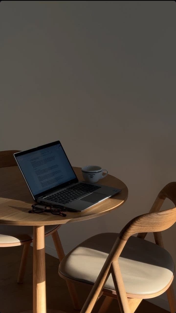 Portátil sobre una mesa redonda de madera con luz cálida de tarde