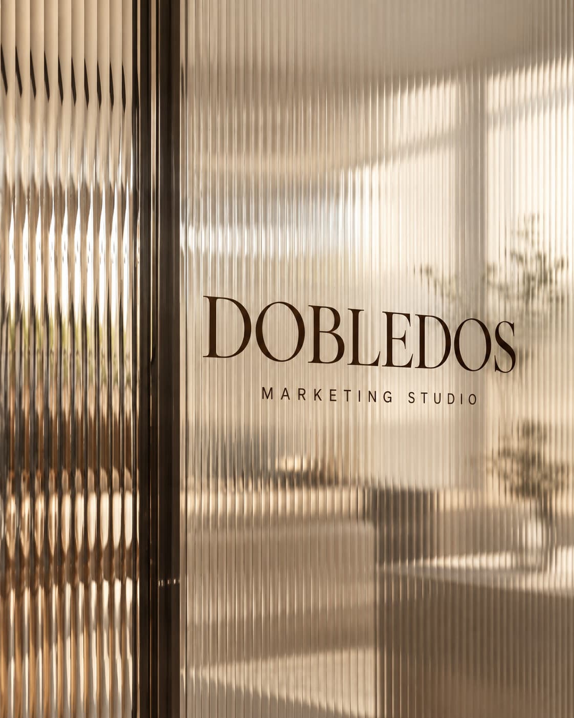 Logotipo de Dobledos tras un cristal acanalado con luz cálida